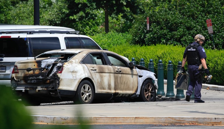A bomb technician walks past an automobile that caught on fire near the Supreme Court in Washington, Wednesday, July 15, 2020. He Supreme Court was not in session during the incident and under investigation.
