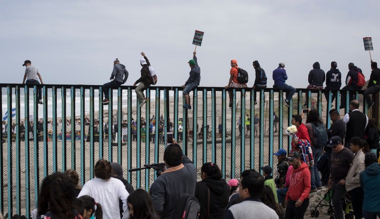 Central American migrants traveling with a caravan gather at the border wall, some sitting on top of it, look toward the U.S. from Mexico during a gathering of migrants living on both sides of the border, on the beach where the border wall ends in the ocean, in Tijuana, Mexico, Sunday, April 29, 2018. U.S. immigration lawyers are telling Central Americans in a caravan of asylum-seekers that traveled through Mexico to the border with San Diego that they face possible separation from their children and detention for many months. They say they want to prepare them for the worst possible outcome.