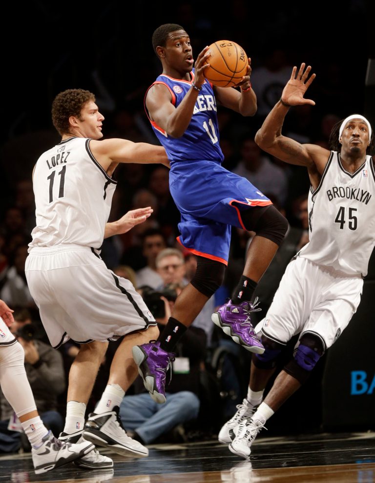   Philadelphia 76ers' Jrue Holiday, center, looks to pass past Brooklyn Nets' Brook Lopez, left, and Gerald Wallace during the first half of an NBA basketball game at the Barclays Center Sunday, Dec. 23, 2012 in New York. (AP Photo/Seth Wenig)  
