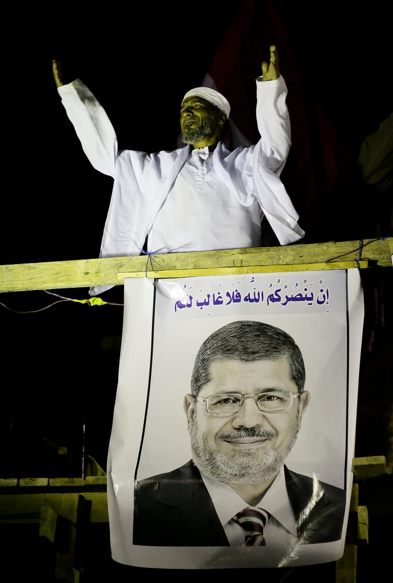   A cleric addresses Islamist protesters supporting Egyptian President Mohammed Morsi, seen on poster, during a protest in front of the Media City complex in Giza, Egypt, Wednesday, Dec. 12, 2012. Egypt's main opposition alliance called for a 