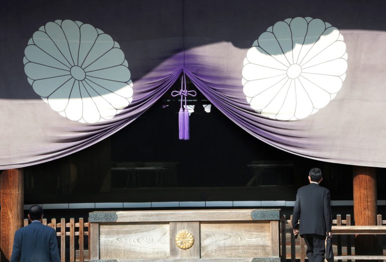 FILE - In this April 23, 2013 file photo, a group of Japanese lawmakers, seen silhouetted in the middle of the photo, offer prayers at the Yasukuni Shrine, which honors Japan's war dead, including World War II leaders convicted of war crimes, in Tokyo during an annual spring festival.  A Japanese Cabinet minister visited the Tokyo shrine that honors the dead including war criminals in what has repeatedly caused friction with Japan's neighbors. Lawmaker Keiji Furuya, who chairs the National Public Safety Commission, said on his website that he paid respects Sunday morning, April 20, 2014, at the Yasukuni shrine ahead of a festival that starts Monday.(AP Photo/Koji Sasahara, File)