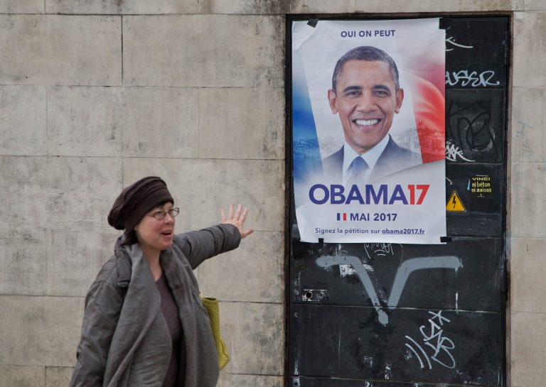 American Sarah Wachter gestures next to a campaign poster with the picture of former U.S. President Barack Obama reading in French 