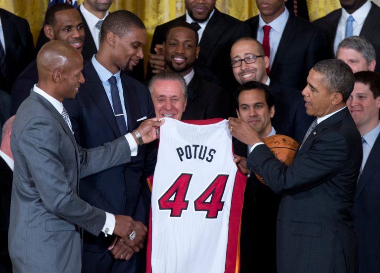 President Barack Obama is given a basketball and jersey by Miami Heat players Ray Allen, left, and Chris Bosh, second from left, during a ceremony in the East Room of the White House in Washington, Tuesday, Jan. 14, 2014, where the president honored the 2013 NBA Champion basketball team . Behind them are Miami Heat forwards LeBron James, and Dwyane Wade, upper left, team president Pat Riley is at center, and Miami Heat head coach Erik Spoelstra is next to Riley. (AP Photo/Carolyn Kaster)