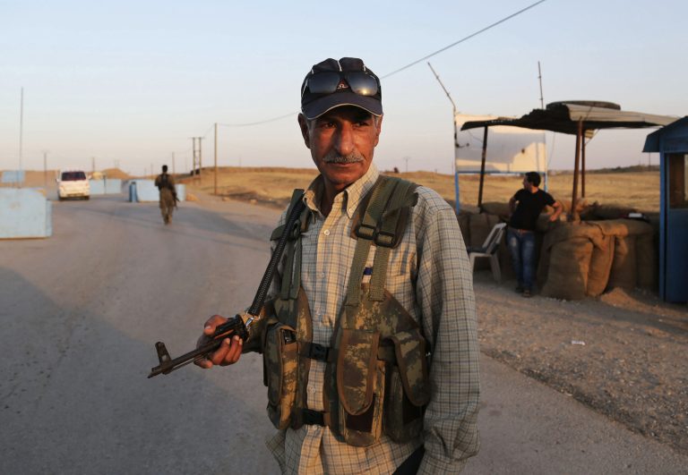 FILE - In this Sunday, Aug. 10, 2014 file photo, Syrian Kurdish Peshmerga fighters stand guard at a refugee camp in Derike, Syria. Islamic State militiamen backed by tanks defiantly marched on in Syria, capturing 21 Kurdish villages even as the international community strains to assemble a coalition that might destroy them. (AP Photo/Khalid Mohammed, File)