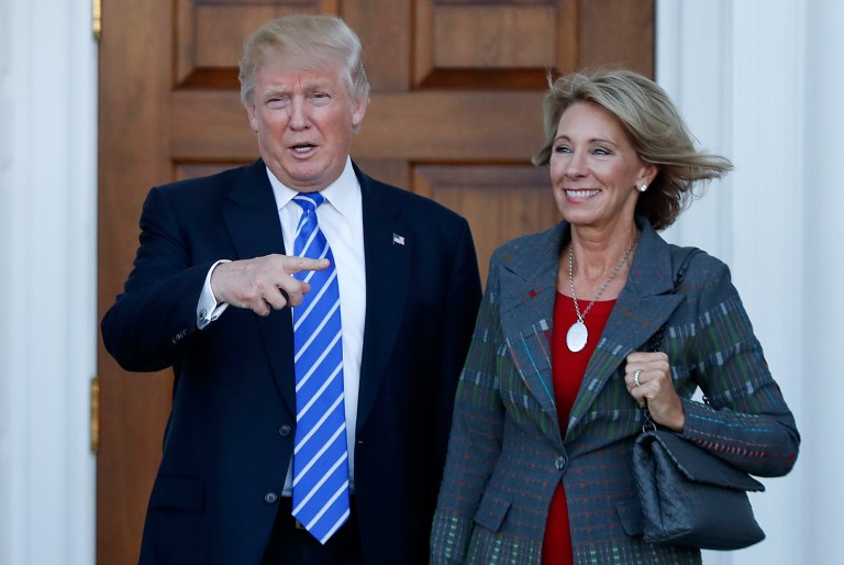 President-elect Donald Trump calls out to the media as he and Betsy DeVos pose for photographs at Trump National Golf Club Bedminster clubhouse in Bedminster, N.J., Saturday, Nov. 19, 2016. (AP Photo/Carolyn Kaster)
