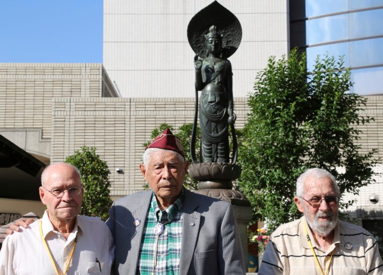 U.S. veterans, William Sanchez, center, 96, of Monterey Park, CA., Oral C. Nichols, left, 93, of Carlsbad, NM., and Jack Schwartz,  99, of Hanford, CA, stand together in front of Heiwajima Kannon by the Heiwajima Motorboat Race stand, the former site of Omori camp, where Sanchez was held before going back to the United States, in Tokyo Thursday, Oct. 16, 2014. The three former POWs are among seven invited by a Japanese government friendship program that has brought five groups of World War II prisoner of war survivors, almost all of them in their 90s, to visit the camps where they were held nearly 70 years ago during the war and speak about their experiences. (AP Photo/Koji Sasahara)