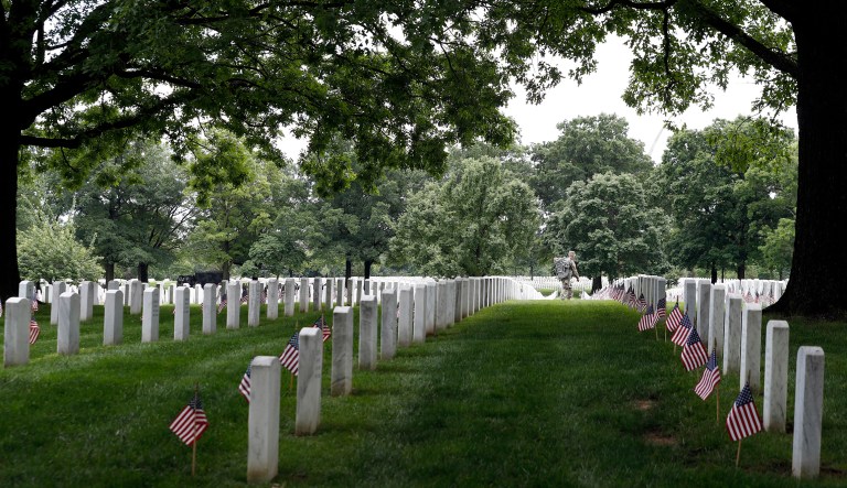 A soldier of the 3d U.S. Infantry Regiment (The Old Guard) walks through headstones as he works during "Flags In," at Arlington National Cemetery, Thursday, May 25, 2017, in Arlington, Va. Soldiers are placing nearly a quarter of a million American flags at the headstones in the cemetery in a Memorial Day tradition.