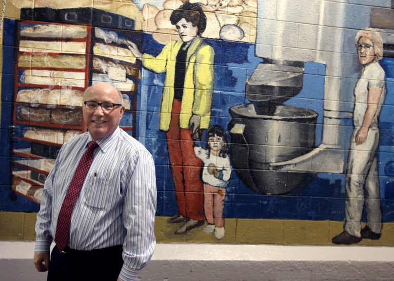 James McColgan CEO of Awrey's Bakery stands by a mural created by a University of Michigan student in 1988, on Feb. 17, 2014 in Livonia, Mich.   It was a year ago that Awrey's Bakery, one of the few remaining iconic Detroit-area brands, avoided permanent closure in a down-to-the-wire purchase deal. The new buyers, Michigan residents Ron Beebe and McColgan, bought the Livonia bakery from a pair of out-of-state private equity firms just hours before its equipment was to be sold at liquidation auction. The 200-some Awrey's employees were already out the door. In their place were auctioneers.  (AP Photo/Detroit Free Press, Jessica J. Trevino)  DETROIT NEWS OUT;  NO SALES