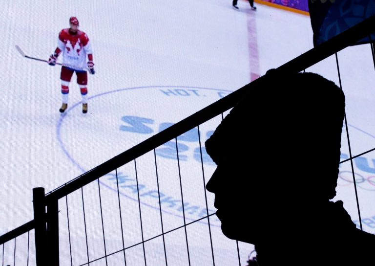 A Russian policeman watches a men's ice hockey match between USA and Russia on a large video screen at an entertainment venue associated with the 2014 Winter Olympics, Saturday, Feb. 15, 2014, in Krasnaya Polyana, Russia. (AP Photo/Charlie Riedel)
