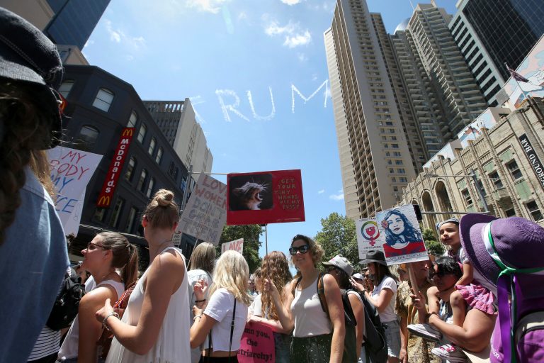 In this Saturday, Jan. 21, 2017 photo, thousands file through the streets during the Women's March protesting the start of Donald Trump's U.S. presidency as a skywriting plane spells out 