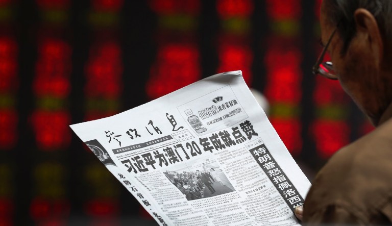 A Chinese investor reads a newspaper with the headlines of Chinese leader Xi Jinping gives achievement like on 20th anniversary of the former Portuguese colony's handover to Chinese rule, at a brokerage house in Beijing, Thursday, Dec. 19, 2019.