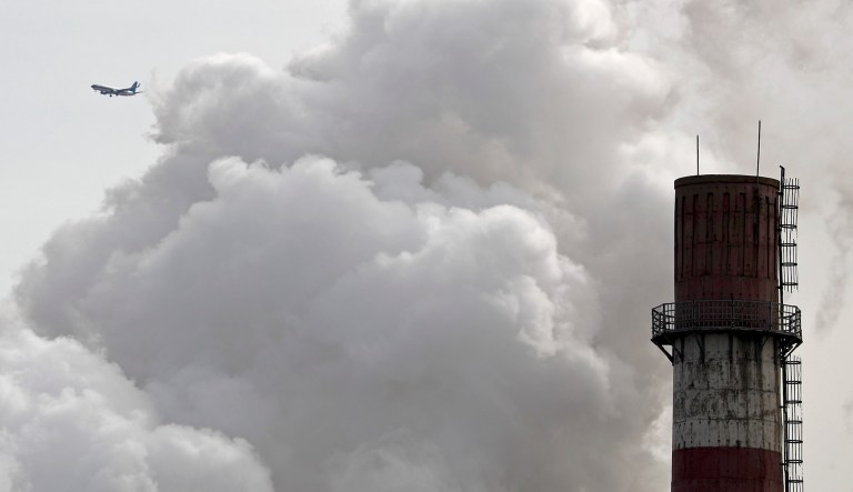 In this file photo taken Tuesday, Feb. 28, 2017, a passenger airliner flies past steam and white smoke emitted from China Huaneng Group's Beijing power plant that was the last coal-fired plant to shut down on March 18, 2017.