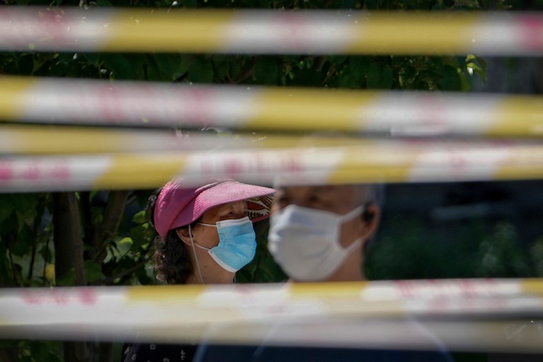 FILE - Residents wearing face masks line up behind barricaded tapes for COVID mass testing near a residential area on May 15, 2022, in Beijing. (AP Photo/Andy Wong, File)