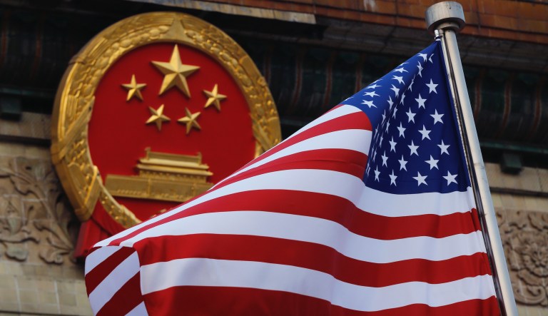 FILE - In this Nov. 9, 2017, file photo, an American flag is flown next to the Chinese national emblem during a welcome ceremony at the Great Hall of the People in Beijing.