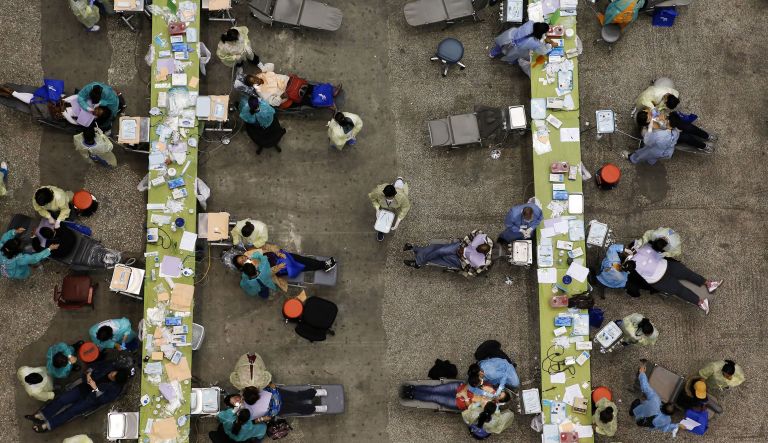 A volunteer carries a tray of dental instruments as patients receive medical attention at a Care Harbor LA free health clinic for the uninsured and underinsured at the Los Angeles Sports Arena in Los Angeles, California, U.S., on Thursday, Oct. 31, 2013.