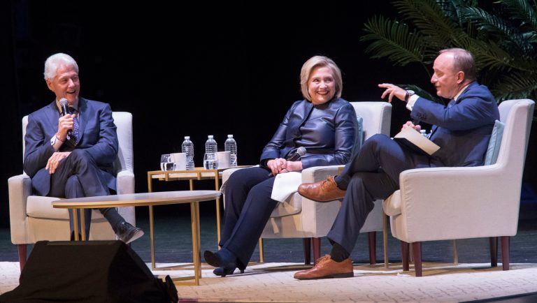 Former President Bill Clinton, left, and former Secretary of State Hillary Rodham Clinton, center, smile as Paul Begala speaks during "An Evening with the Clintons", Thursday, April 11, 2019, at the Beacon Theatre in New York. 