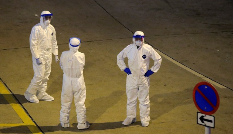 Personnels wearing protective suits wait at the Cheung Hong Estate, a public housing estate during evacuation of residents in Hong Kong, Tuesday, Feb. 11, 2020. The Centre for Health Protection of the Department of Health evacuated some residents from a public housing estate after two cases of novel coronavirus infection to stop the potential risk of further spread of the virus.