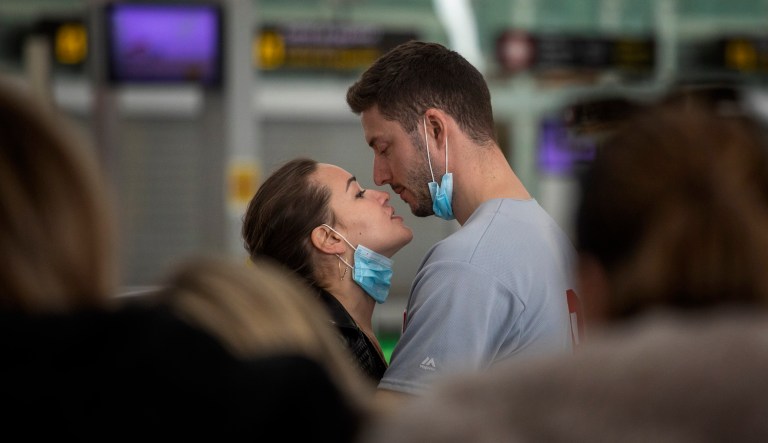 A couple kiss,  at the Barcelona airport, Spain, Thursday, March 12, 2020. President Donald Trump, who had downplayed the coronavirus for weeks, suddenly struck a different tone, announcing strict rules on restricting travel from much of Europe to begin this weekend. For most people, the new coronavirus causes only mild or moderate symptoms, such as fever and cough. For some, especially older adults and people with existing health problems, it can cause more severe illness, including pneumonia.