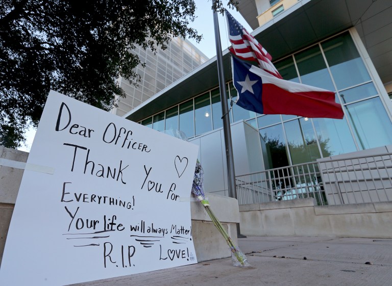 An American flag and a Texas state flag fly at half-staff at San Antonio Police Department headquarters after Det. Benjamin Marconi was fatally shot Sunday in San Antonio. Marconi was writing out a traffic ticket to a motorist when he was shot to death in his squad car Sunday outside police headquarters. (Edward A. Ornelas/The San Antonio Express-News via AP)