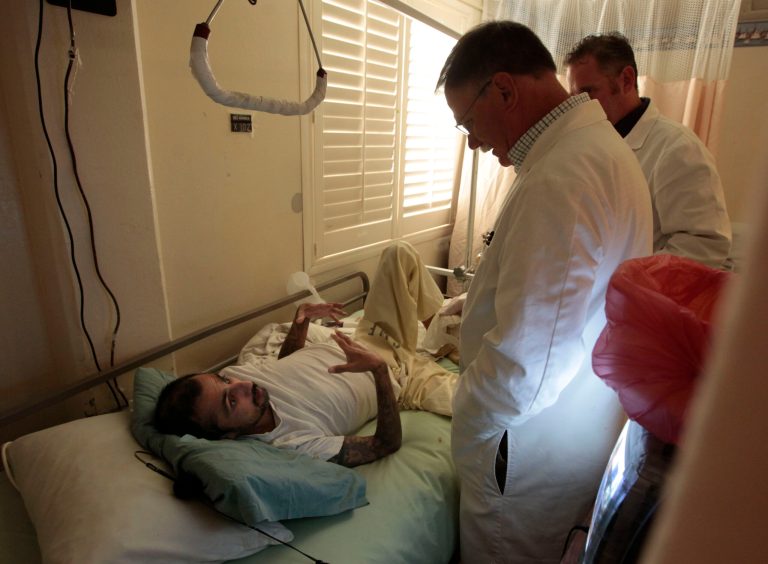In this photo taken Wednesday, Sept. 12, 2012, Dr. David Mathis, center, talks with a cancer patient, inmate Luis Duran, in the hospice unit at the California Medical Facility in Vacaville, Calif. (AP Photo/Rich Pedroncelli)