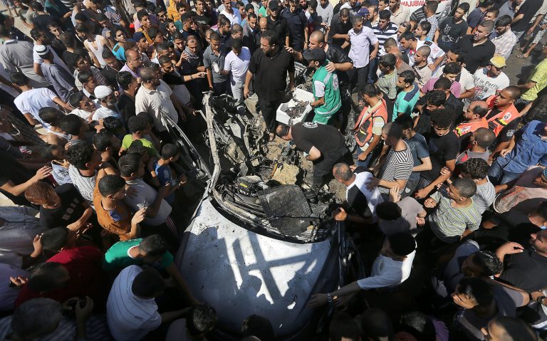 Palestinians gather around wreckage after an airstrike in the Shati refugee camp in Gaza City on Friday, June 27, 2014. Palestinian officials said at least two people were killed in an Israeli airstrike in Gaza. Earlier, Israel's military said it fired at Hamas targets in Gaza after an explosive device was deployed against troops on the border, causing no injuries. (AP photo/Hatem Moussa)
