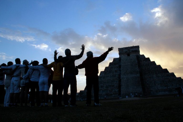   People gesture toward the the Kukulkan temple in Chichen Itza, Mexico, Friday, Dec. 21, 2012. Ceremonial fires burned and conches sounded off as dawn broke over the steps of the main pyramid at the Mayan ruins of Chichen Itza Friday, making what many believe is the conclusion of a vast, 5,125-year cycle in the Mayan calendar. Some have interpreted the prophetic moment as the end of the world. The hundreds gathered in the ancient Mayan city, however, said they believed it marked the birth of a new and better age. (AP Photo/Israel Leal)  