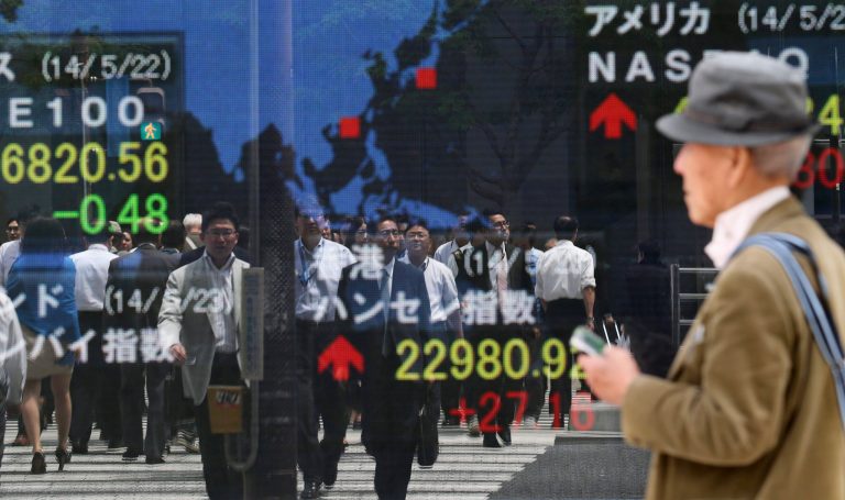 A passer-by looks at an electronic stock board of a securities firm in Tokyo, Friday, May 23, 2014. Japan's Nikkei 225 was up 0.9 percent at 14,473.19 after the dollar climbed to near 102 yen overnight. A weaker yen is a plus for Japan's powerhouse export manufacturers. (AP Photo/Koji Sasahara)