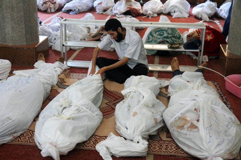 A man holds the body of a supporter of ousted President Mohammed Morsi at the El-Iman mosque in Cairo's Nasr City, Egypt, Thursday. Egyptian authorities said hundreds of people died and the government to declare a nationwide state of emergency and a nighttime curfew. The violence began when Egyptian security forces stormed two makeshift camps to clear out Morsy supporters. (AP Photo/Ahmed Gomaa)
