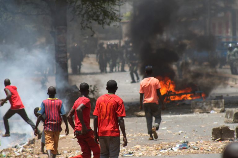 Opposition protestors lighting burning street barricades clash with security forces firing tear gas, in Conakry, Guinea, Thursday, April 18, 2013. Security forces in Guinea arrested the opposition's spokesman and another leader Thursday after firing tear gas to disperse protesters who had planned a demonstration against the date set for upcoming legislative elections. The long-awaited vote has been a flashpoint for violent demonstrations over the last several months in this West African nation that long suffered under strongman rule. (AP Photo/Youssouf Bah)
