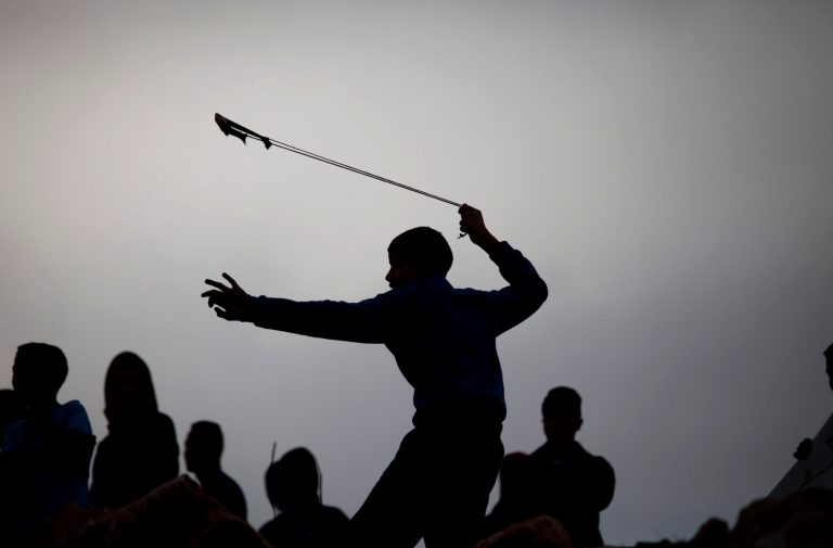 A Palestinian protester using a sling shot throws a stone towards Israeli security forces during clashes following a protest against Israeli restrictions on the Al-Aqsa Mosque in Jerusalem, at the Qalandia checkpoint near the West Bank city of Ramallah, Friday, Nov. 21, 2014.(AP Photo/Majdi Mohammed)