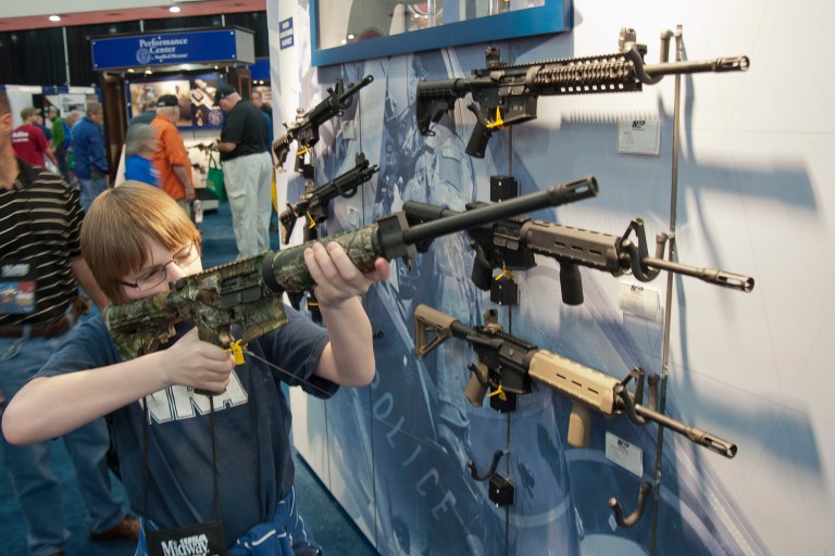 A young man who chose not to give his name sizes-up an assault style rifle during the National Rifle Association's annual convention Friday, May 3, 2013 in Houston. (AP Photo/Steve Ueckert)