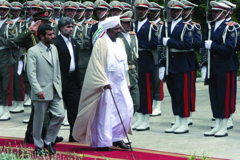 FILE - Sudanese President Omar al-Bashir, center, and Iranian President Mahmoud Ahmadinejad, left, review an honor guard, in Tehran, Iran, in this Wednesday, April, 26, 2006 file photo. Explosions at a military site near Sudan's capital Khartoum on Oct 23 2012, widely believed to be the result of an Israeli airstrike, point to a possible escalation in a hidden front of the rivalry between Iran and Israel which believes arms pipeline through Sudan to Islamic militants on Israel's borders. (AP Photo/Hasan Sarbakhshian, file)