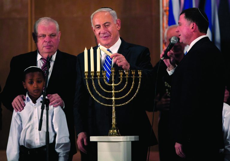 Israeli Prime Minister Benjamin Netanyahu lights candles on the Jewish holiday of Hanukkah during an event with foreign press in Jerusalem, Monday, Dec. 10, 2012. Netanyahu is accusing the international community of double standards, saying it condemns Israeli settlements in the West Bank but not Palestinians' refusal to renew peace talks or militant group Hamas' call for the end of the Jewish state. (AP Photo/Sebastian Scheiner)