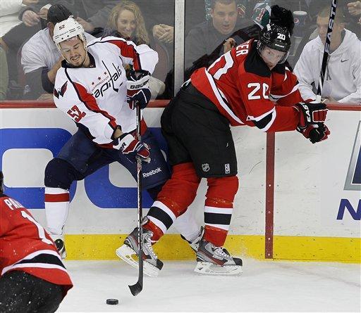 Washington Capitals' Mike Green (52) controls the puck despite being hit into the boards by New Jersey Devils' Ryan Carter (20) during the first period of an NHL hockey game, Friday, Nov. 11, 2011, in Newark, N.J.
