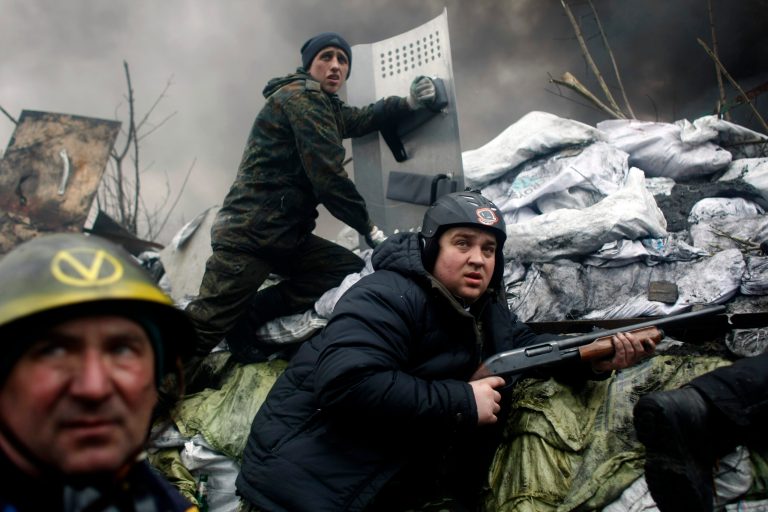 An anti-government protester wields a firearm as he mans a barricade on the outskirts of Independence Square in Kiev, Ukraine, on Thursday. (AP Photo/ Marko Drobnjakovic)