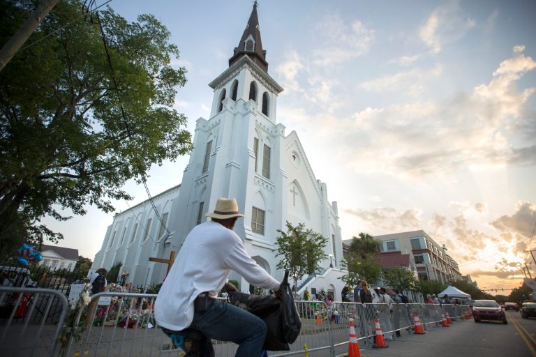 A bicyclist rides in front of the Emanuel AME Church, Sunday, June 21, 2015, before the first worship service since nine people were fatally shot at the church during a Bible study group, in Charleston, S.C. (AP Photo/Stephen B. Morton)