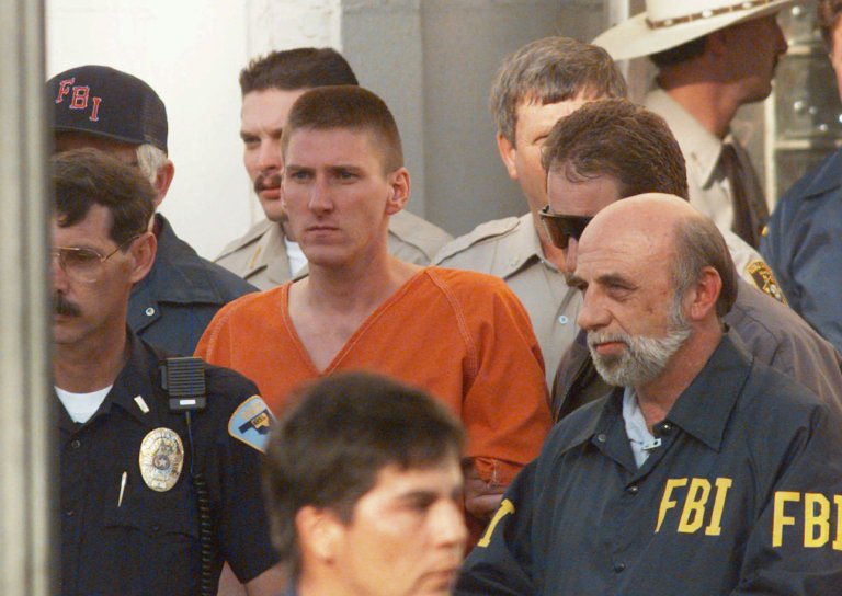 Timothy McVeigh is escorted by law enforcement officials from the Noble County Courthouse in Perry, Okla., April 21, 1995, two days after the bombing of the Alfred P. Murray Federal Building that claimed the lives of 168 people. (AP Photo/David Longstreath, File)