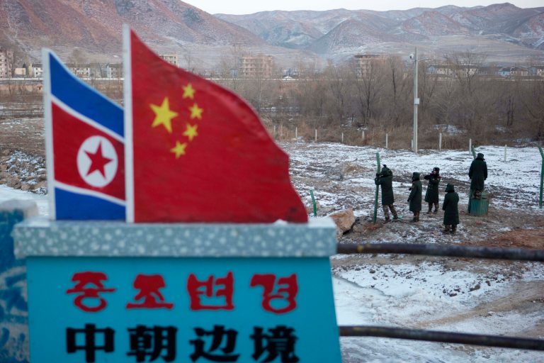   In this Saturday, Dec. 8, 2012 photo, Chinese paramilitary policemen build a fence near a concrete marker depicting the North Korean and Chinese national flags with the words 