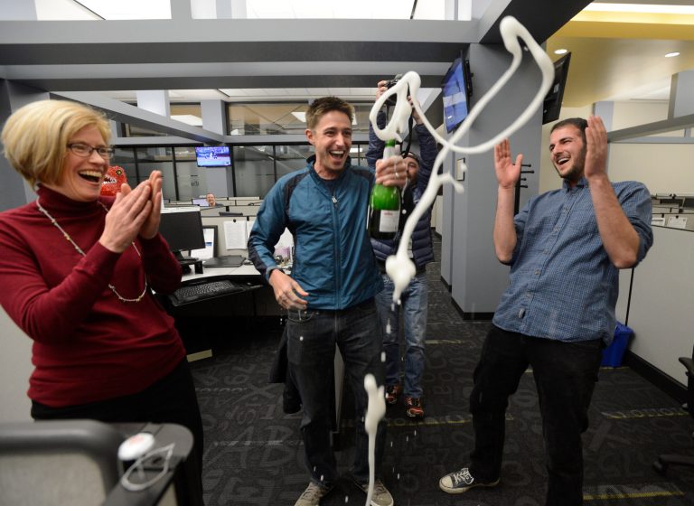 Colorado Springs Gazette reporter David Philipps, center, pops the cork during a Pulitzer Prize celebration in the Gazette newsroom Monday in Colorado Springs, Colo. (Colorado Springs Gazette)