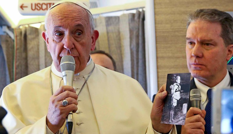Pope Francis holds a picture showing a Nagasaki victim as he speaks to journalists onboard the plane for his trip to Chile and Peru. 