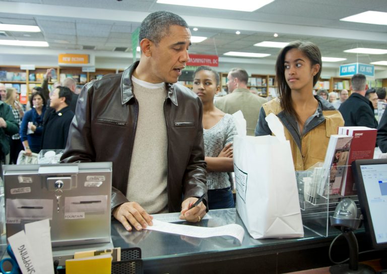 President Barack Obama, with daughters Sasha, center, and Malia, pays for his purchase the the local bookstore Politics and Prose in northwest Washington, Saturday, Nov. 30, 2013.  (AP Photo/Manuel Balce Ceneta)