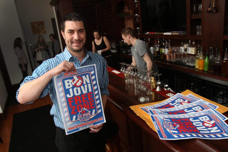 In this May 21, 2014 photo, Anthony Lynch displays a Bon Jovi Free Zone poster at Savoy in Buffalo, N.Y. The New Jersey rocker has been linked to a Toronto-based developer interested in purchasing a franchise and moving it to Canada's largest city. (AP Photo/The Buffalo News, Sharon Cantillon)
