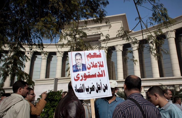   A supporter of Egyptian President Mohammed Morsi holds a banner with his picture and Arabic that reads, 