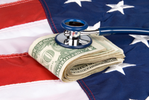 A pile of cash on an American flag with a stethoscope on the money, inferring anything from medical costs to economic health and financial stability.