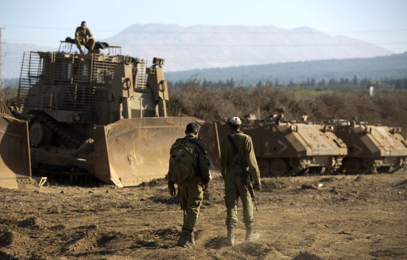 Israeli soldiers walk next to an armoured bulldozer in an army deployment training area in the Israeli-annexed Golan Heights near the border with Syria on August 28, 2013. (MENAHEM KAHANA/AFP/Getty images)