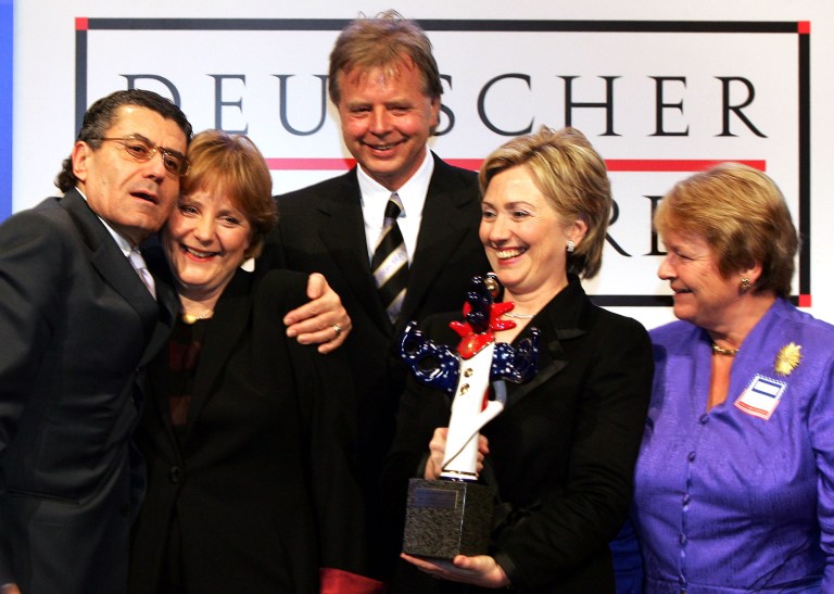 Hillary Clinton appears with Karlheinz Koegel, center, German Chancellor Angela Merkel, second from left, U.S. billionaire Haim Saban, left, and former Norwegian Prime Minister Gro Brundtland, holding the German Media Prize she was awarded in Baden-Baden, southern Germany, in this Feb. 13, 2005, file photo. (AP Photo/Winfried Rothermel, File)
