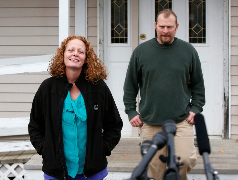 Kaci Hickox and her boyfriend Ted Wilbur come out of their house to speak to reporters, Friday, Oct. 31, 2014, in Fort Kent, Maine. Hickox, a nurse who defied an Ebola quarantine in the state of Maine after treating patients in West Africa, can travel unrestricted after a judge rejected the state's bid to limit her movements. Judge Charles C. LaVerdiere said Friday that Hickox must continue daily monitoring and co-ordinate travel with state officials so monitoring can continue. But the judge said there's no need for further restrictions because she's not infectious. (AP Photo/Robert F. Bukaty)