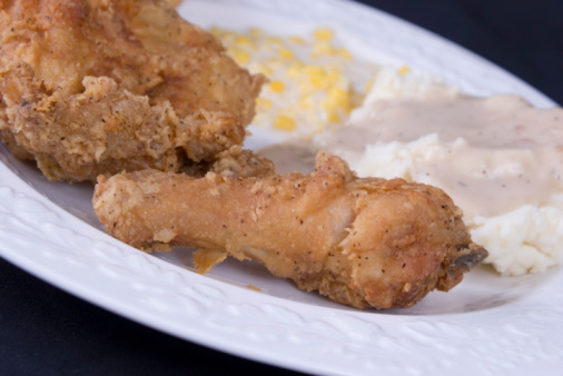 Close-up of a Southern homestyle dinner with chicken, mashed potatoes and gravy, creamed corn and baking powder biscuit.