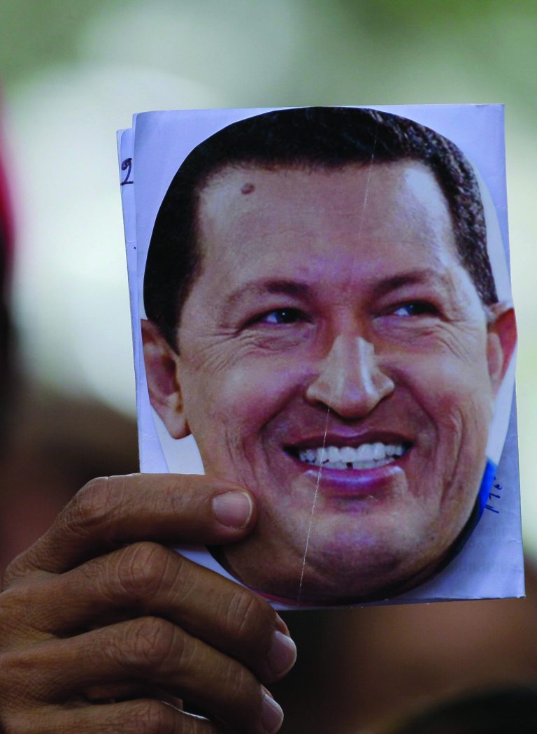 A person holds up an image of Venezuela's President Hugo Chavez during a demonstration in support of him at the Simon Bolivar square in Caracas, Venezuela, Sunday Dec. 9, 2012. Chavez was heading back to Cuba on Sunday for more cancer surgery after announcing that the illness returned despite two previous operations, chemotherapy and radiation treatment. Chavez said Saturday that if there are 