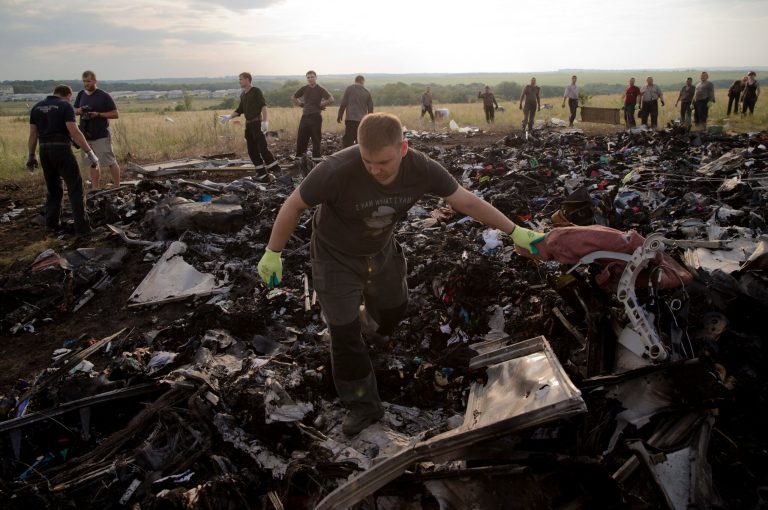 A man looks for the remains of victims in the debris at the crash site of Malaysia Airlines Flight 17 near the village of Hrabove, eastern Ukraine, Saturday, July 19, 2014. World leaders demanded Friday that pro-Russia rebels who control the eastern Ukraine crash site of Malaysia Airlines Flight 17 give immediate, unfettered access to independent investigators to determine who shot down the plane. (AP Photo/Vadim Ghirda)